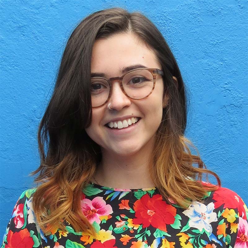 Mariana smiling in front of a blue wall.